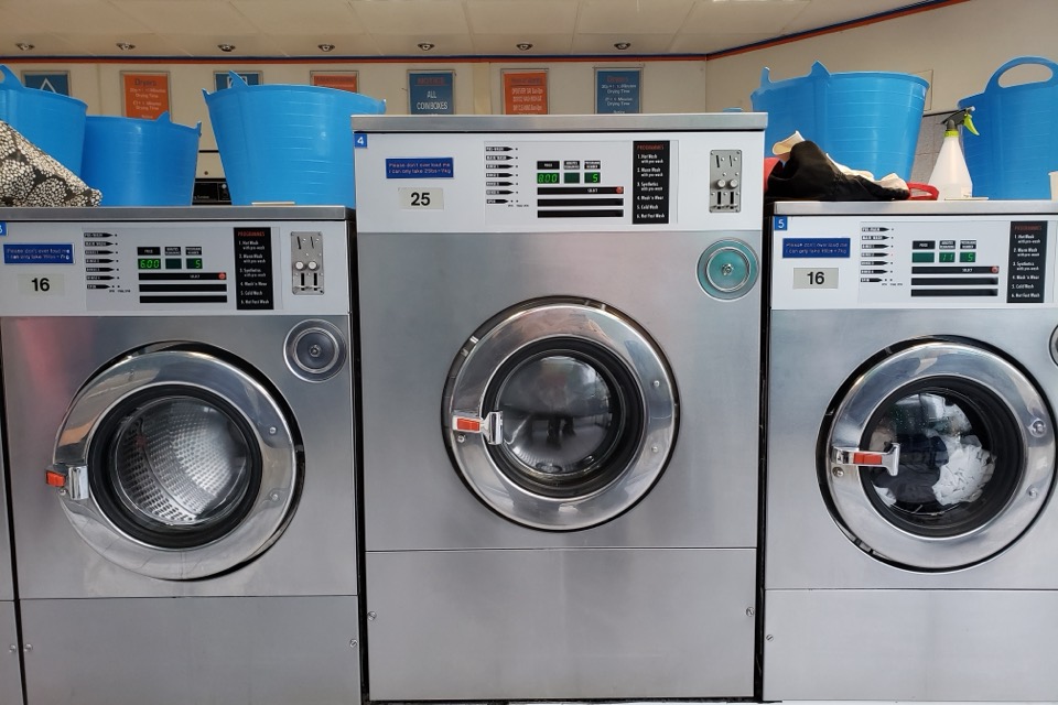Three commercial coin-operated washing machines side by side
